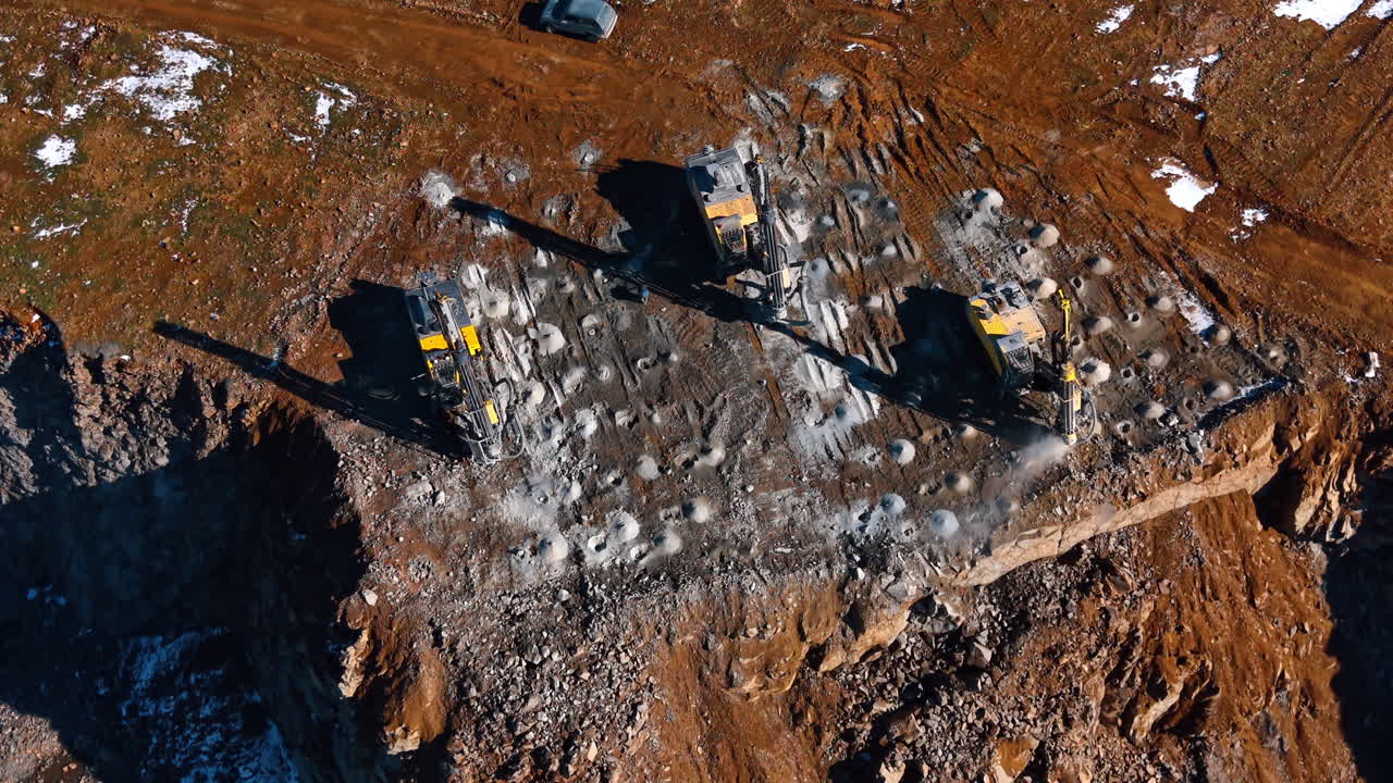 Building in a rocky quarry. Heavy machinery operates on rocky ground to drill and shape the land in a quarry during daytime hours