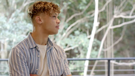 young man in striped shirt gazing thoughtfully outside, enjoying nature view, copy space