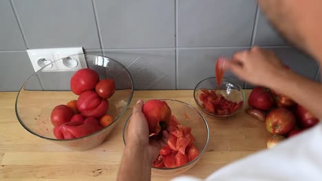 la mano del hombre cortando y pelando el tomate, usando un cuchillo pequeño y afilado en la cocina de una casa