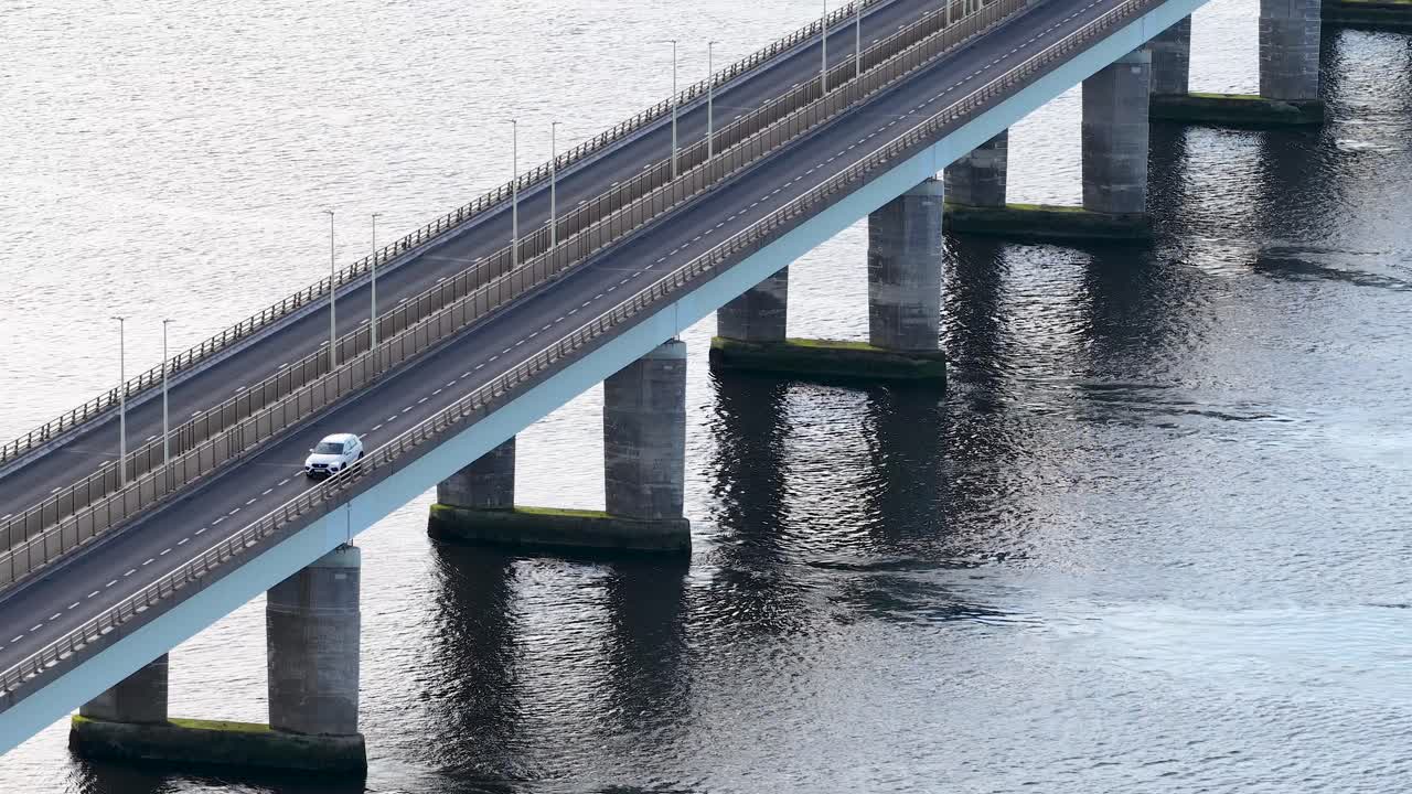 A lone car crosses Tay Road Bridge over calm river water in steady daylight