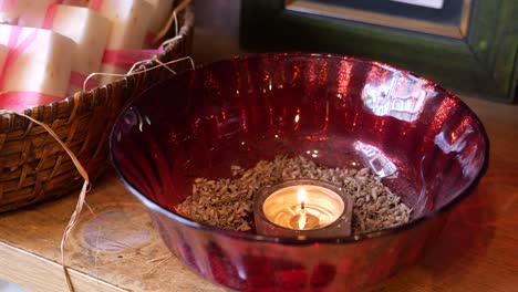 a lit candle in a red bowl with lavender