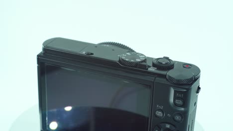 close up shot of a small black pocket camera, aluminiaum built, on a 360 rotating stand, function buttons, slow motion, 4k video