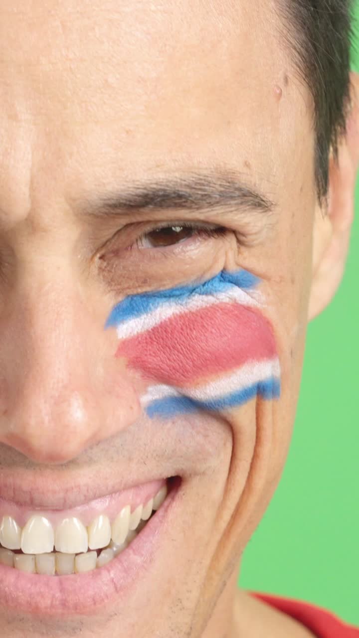 Man with a costa rican flag painted on the face smiling