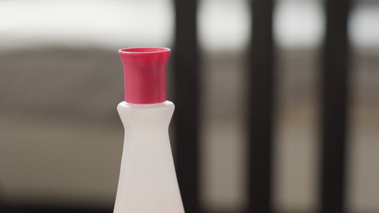 Close up smooth female hands gently closing cap on white nail polish remover bottle, careful twist motion, cosmetic hygiene routine at home, soft skin detail, pink lid, clean fingertips