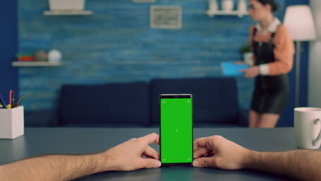 Point-of-view-freelencer-man-in-office-studio-holding-mock-up-green-screen-chroma-key-phone