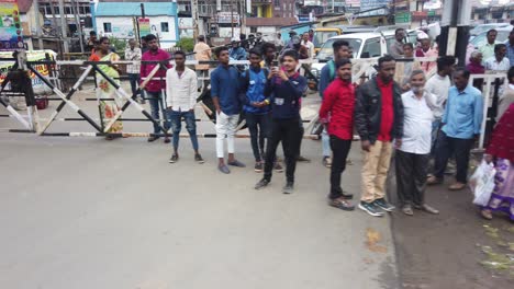tourists, pedestrians and traffic wait at level crossing for nilgiri mountain railway train to pass at ooty, udagamandalam, ootacamund, udhagai, tamil nadu, india.