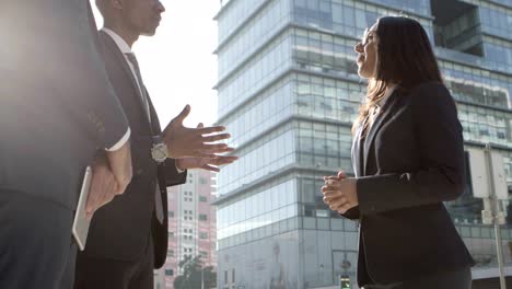 Business-people-shaking-hands-and-talking-outdoors