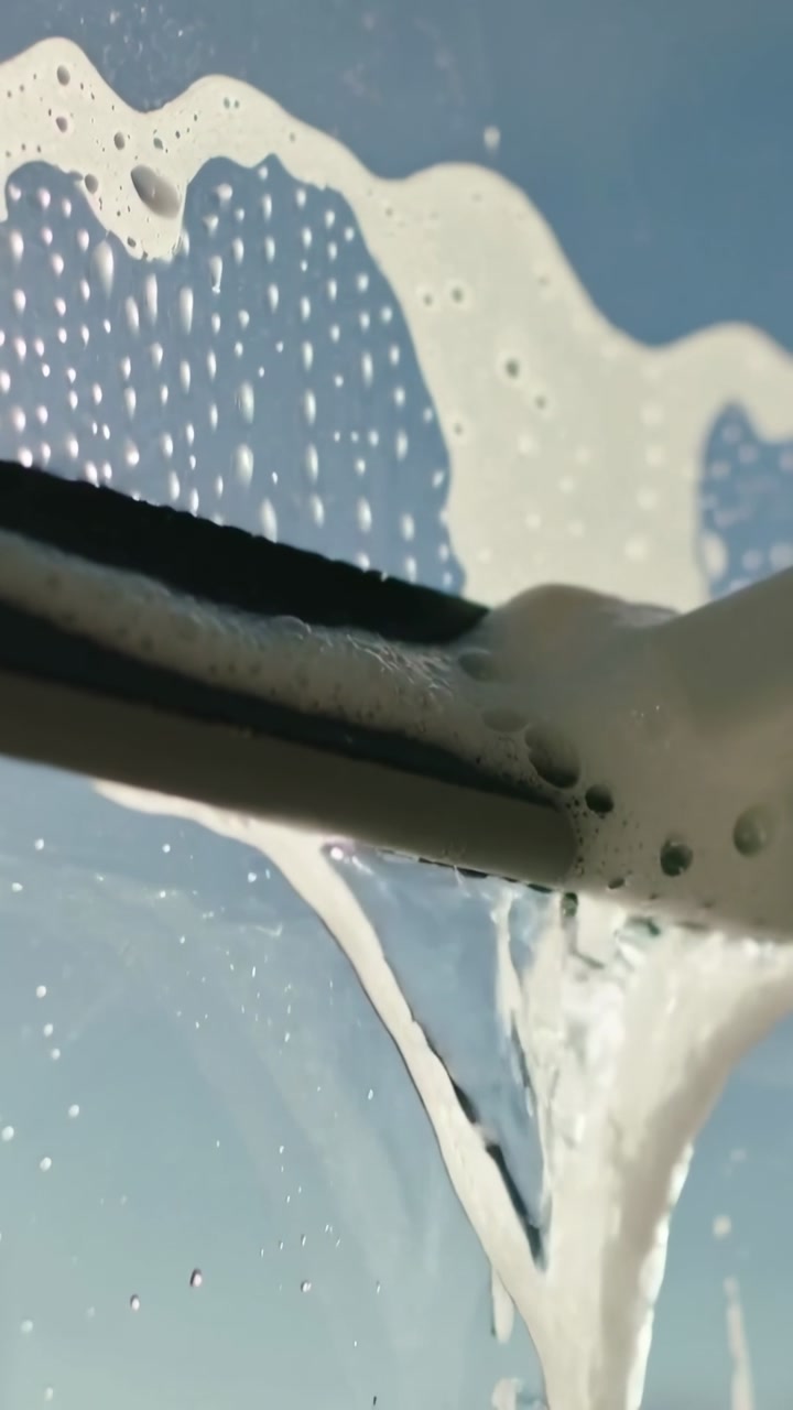 Vertical video: Entering lower left, wiper blade dragging foam across glass, showing blue sky mesh