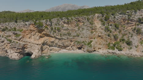 aerial 5k drone flyover secluded cliffside beach with clear turquoise sea in dubrovnik, croatia