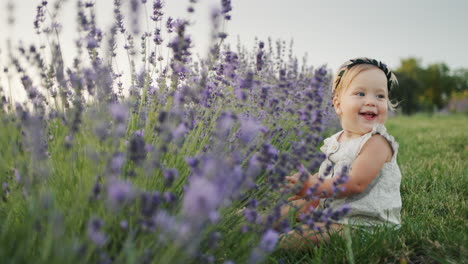 Portrait-of-a-fair-haired-happy-girl,-sits-near-a-lavandin-bush,-smiles