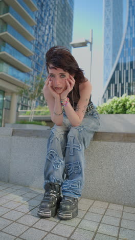 Vertical-Video-Outdoor-Fashion-Portrait-Of-Young-Alternative-Style-Woman-With-Tattoos-And-Piercing-Sitting-Outside-Modern-Buildings-At-Canary-Wharf-London-Shot-In-Real-Time-1