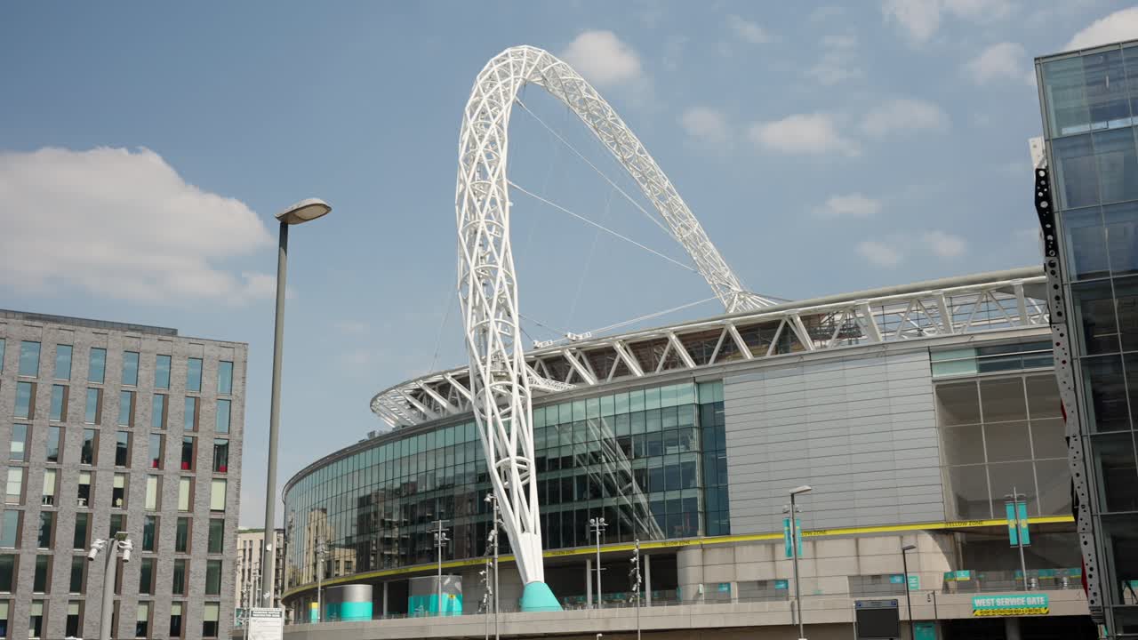 Exterior shot panning left across Wembley Stadium on sunny day in London