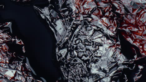 crumpled foil with dark liquid and red stain