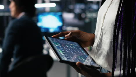 close up of data center engineer using tablet to review code