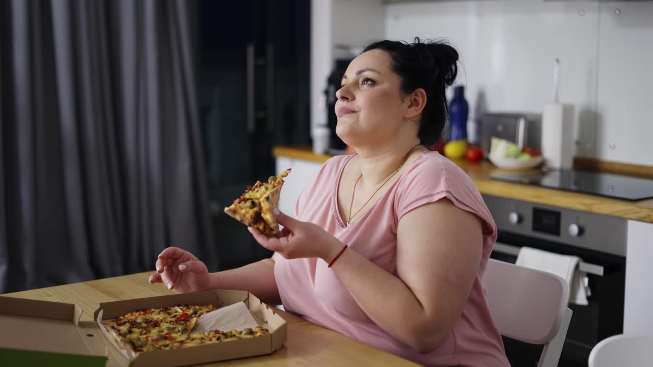 Overweighted woman eats with great pleasure, woman eats pizza, rolls eyes