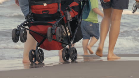 a red baby carriage being moved along the beach