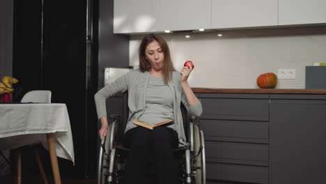 woman after surgery reads book and eats fruits in kitchen