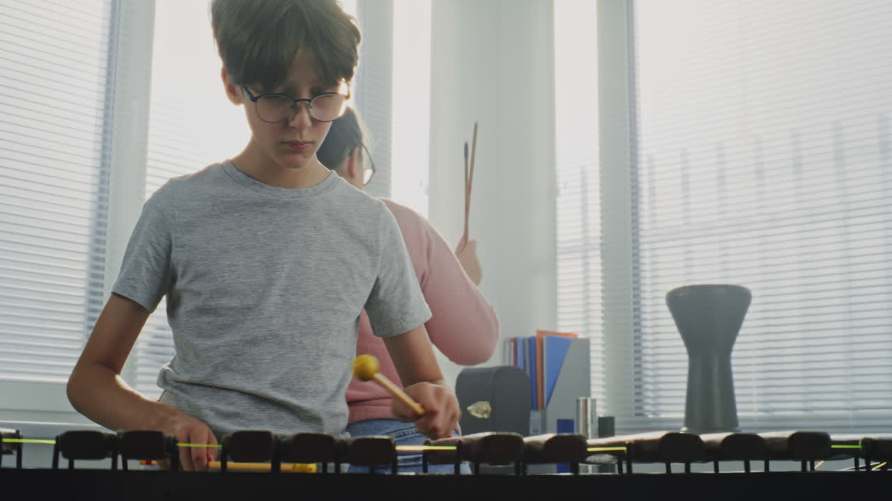 A boy and a woman are playing a musical instrument indoors