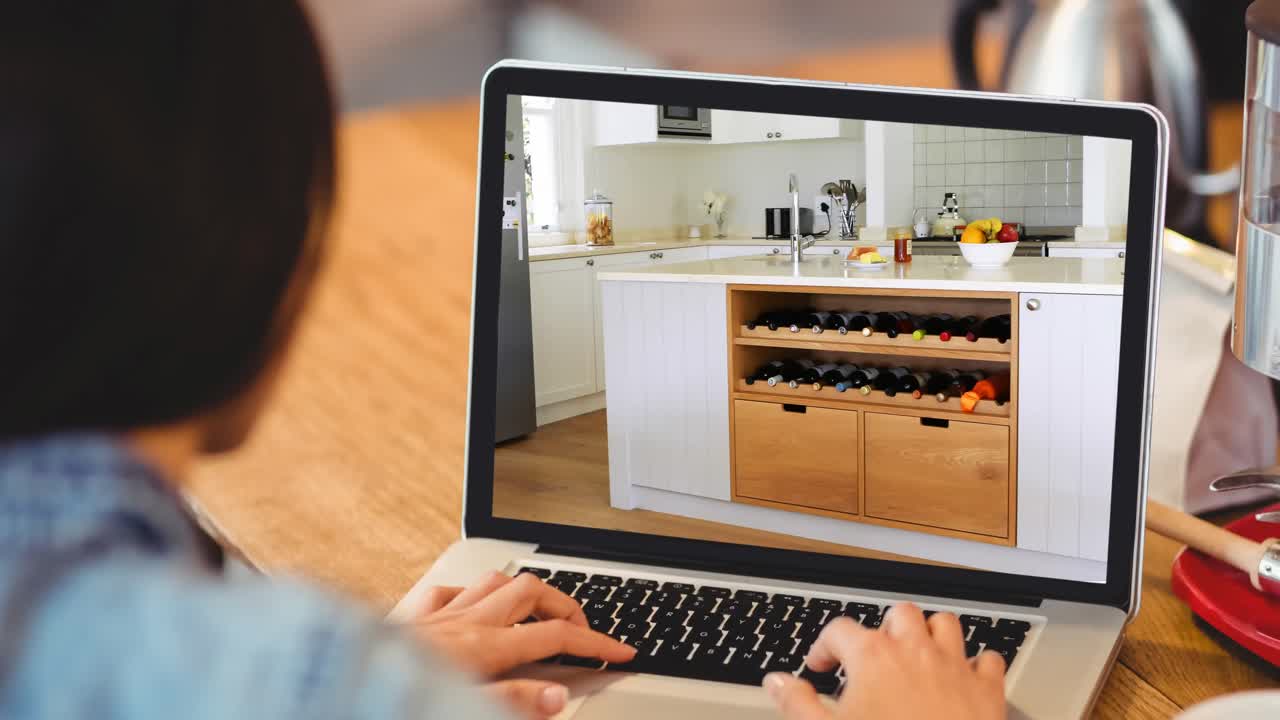 mujer usando una computadora portátil con interiores de cocina modernos mostrados en la pantalla