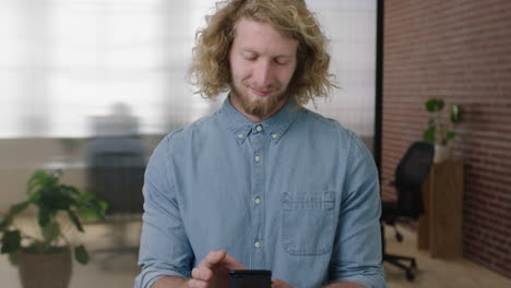 portrait-of-young-charming-blonde-man--texting-browsing-using-smartphone-social-media-app-checking-messages-in-office-workspace