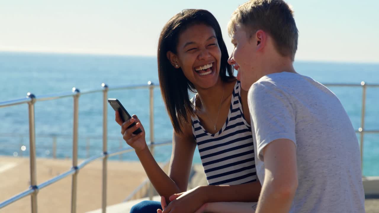 pareja feliz usando teléfono móvil cerca de las barandillas 4k