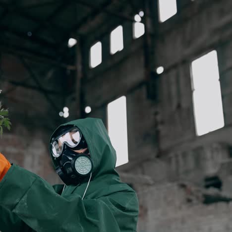 Survivor with flowers in infected zone. Human in protective suit and gas mask holding flowers in abandoned building. Save the nature. Ecological disaster