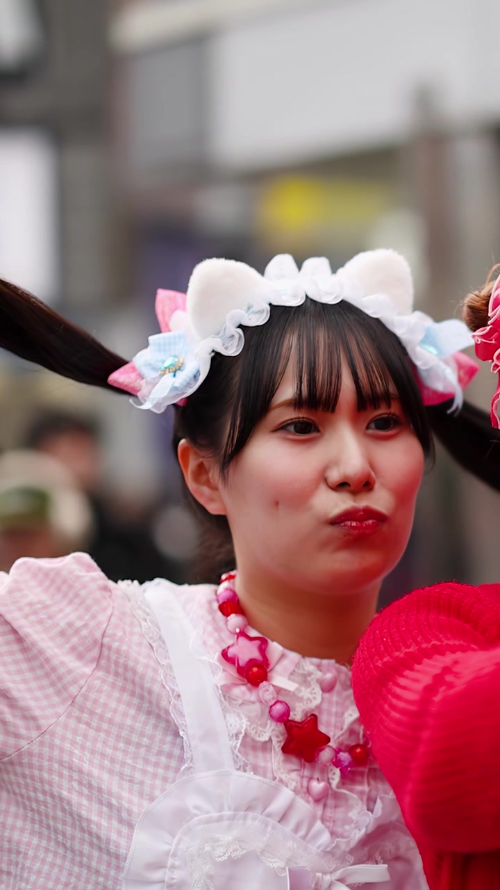 Giovane donna con vivaci abiti decora posa per un selfie in una strada di Harajuku