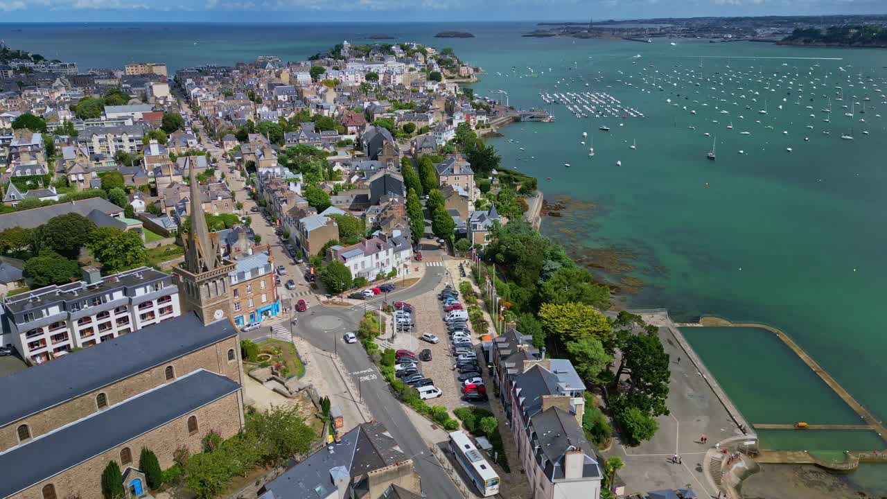 Aerial drone of Dinard cityscape, Notre Dame d'Emeraude church, seawater pool, and marina full of sailboats, France. Aerial drone panoramic view