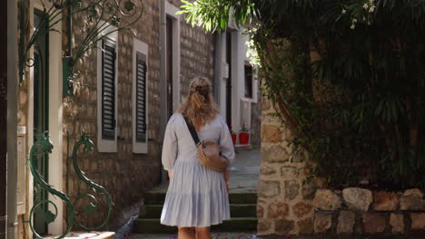 back of blonde wander in herceg novi old town neighborhood in montenegro