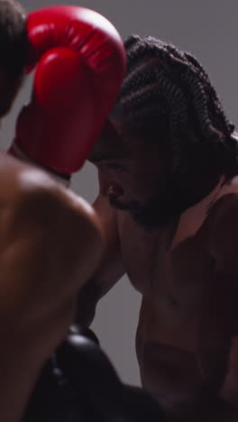 vertical video close up studio shot of two male boxers wearing gloves fighting in boxing match