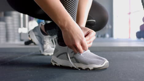 tying shoelaces, woman preparing for workout in gym, wearing athletic shoes