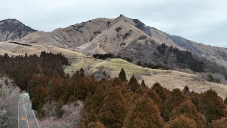 Drone-flight-over-lush-trees-in-Aso,-Kumamoto-Prefecture,-Japan,-showcasing-the-stunning-natural-landscape-of-mountains-and-hills