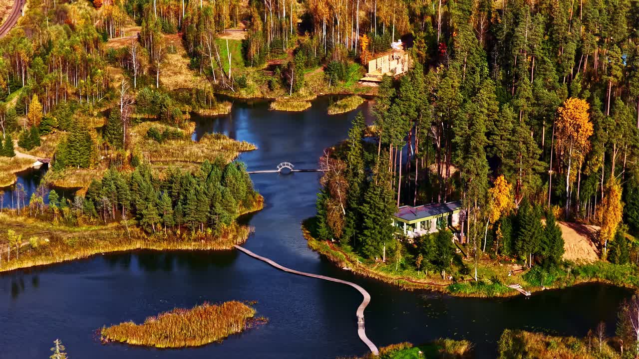 Aerial of lake surrounded by autumn forest and vibrant reflections in water, community complex