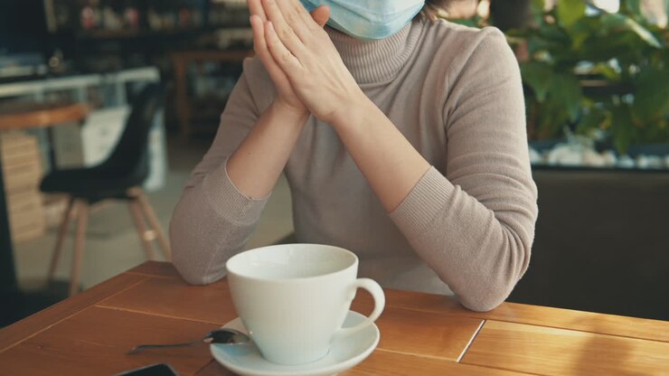 Portrait de jeune femme avec un masque parlant à son amie dans un café