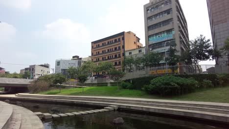 urban park with a pond in foreground, modern buildings in the background, overcast day