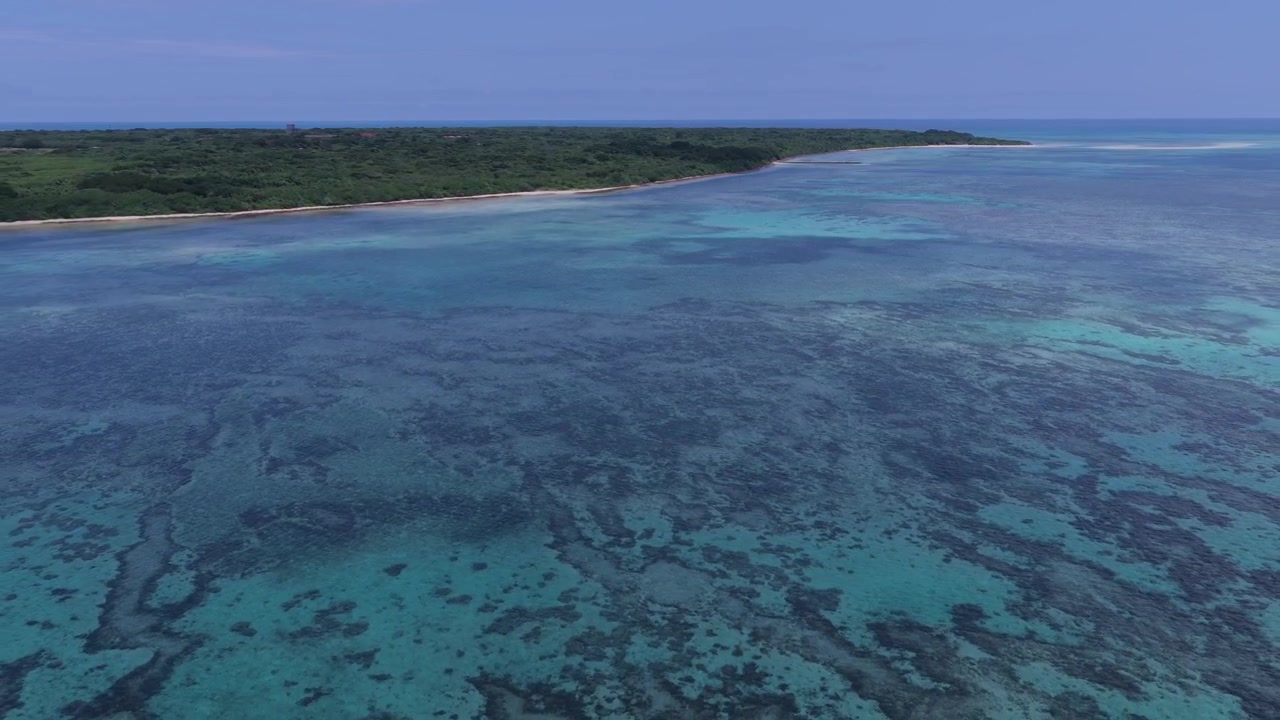 Riprese aeree orizzontali con carrello all'indietro sopra le vaste barriere coralline e le acque turchesi del Molo Nishi e della Spiaggia di Kondoi, Isola di Taketomi, Okinawa, Giappone