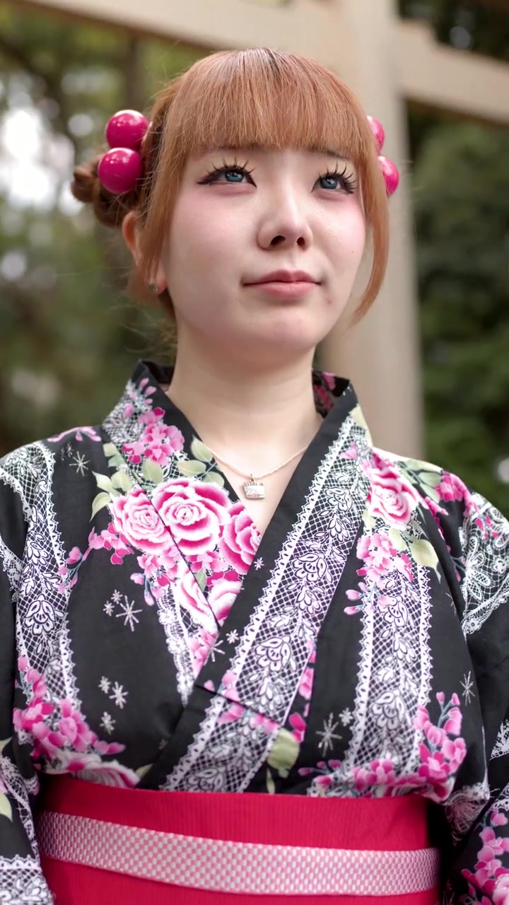 Một phụ nữ Nhật Bản mặc kimono họa tiết hoa đứng bên ngoài một ngôi đền dưới ánh sáng ban ngày dịu nhẹ