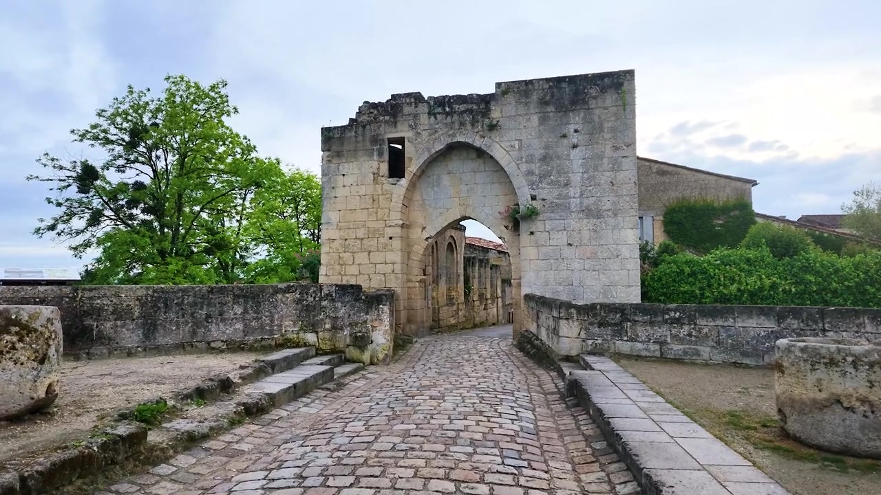Una lenta carrellata in avanti si muove verso un arco medievale in pietra calcarea lungo strade acciottolate.