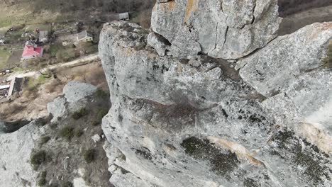 vista aérea de una cara de acantilado rocoso con un pueblo debajo