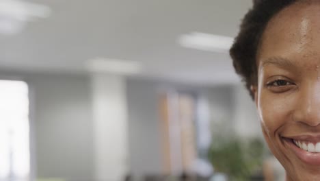 Half-portrait-of-happy-african-american-businesswoman-in-office,-smiling,-in-slow-motion,-copy-space