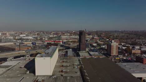 Aerial-panoramic-view-of-highway-passing-through-commercial-town-borough.-Production-or-logistic-halls-along-road.-Queens,-New-York-City,-USA