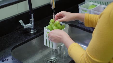washing green grapes in a kitchen sink