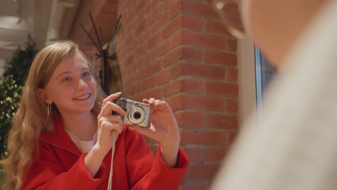 Giovane donna sorridente che scatta una foto con una fotocamera digitale in un bar
