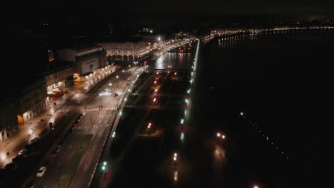 bordeaux city lights along garonne river at night - aerial