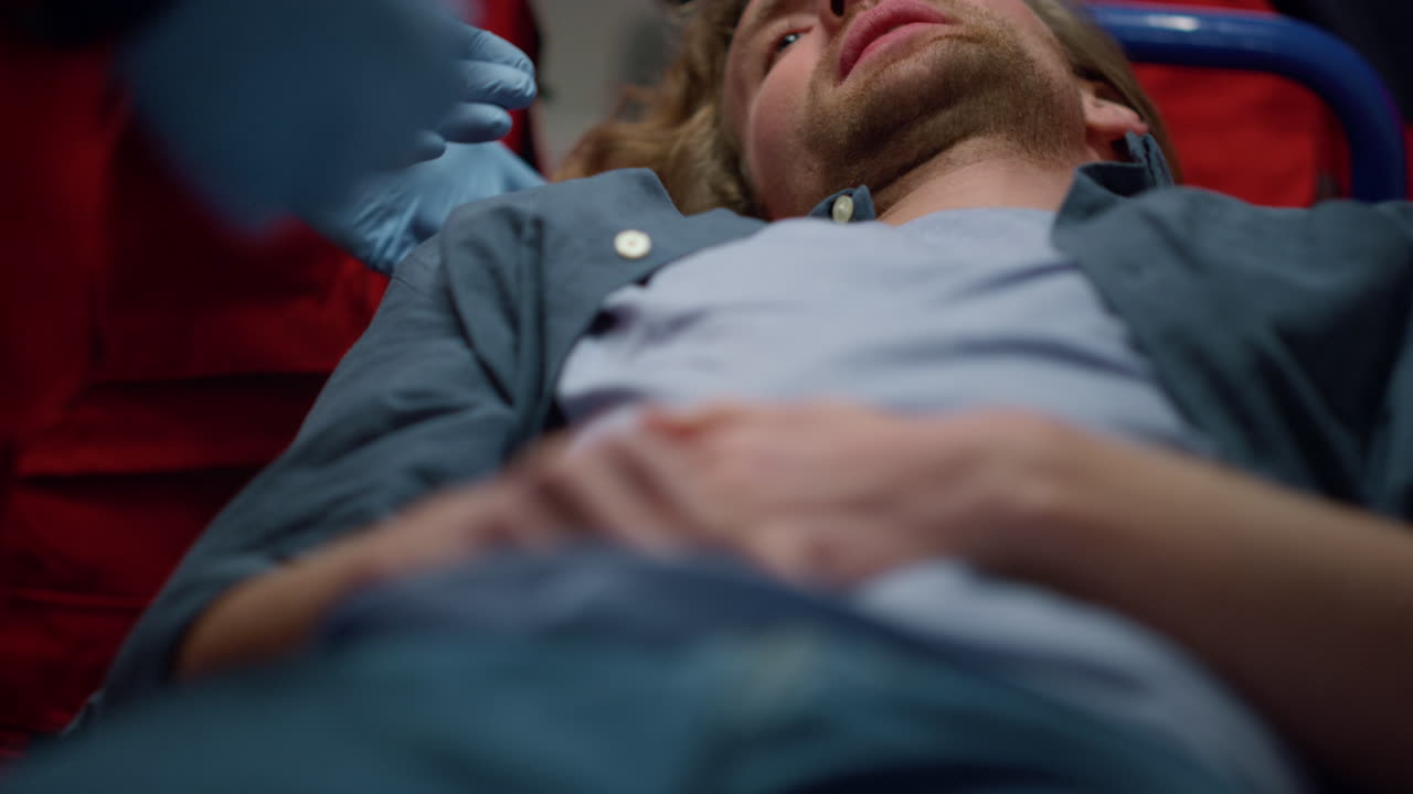 hombre acostado en camillas en el coche de primeros auxilios. paciente masculino sintiendo dolor en el abdomen