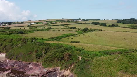 Traeth-Lligwy-Anglesey-eroded-coastal-shoreline-aerial-view-panning-across-scenic-green-rolling-Welsh-weathered-coastline