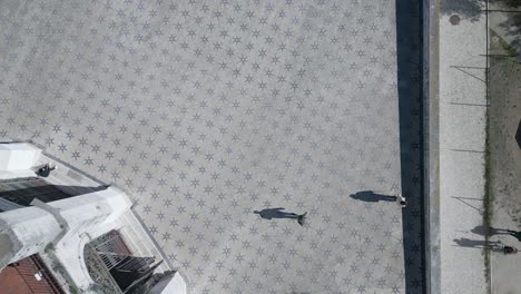 Vertikale-Luftaufnahme-Eines-Historischen-Wohnviertels-In-Lissabon,-Portugal,-Mit-Menschen,-Die-Spazieren-Gehen-Und-Wunderschöne-Schatten-Werfen