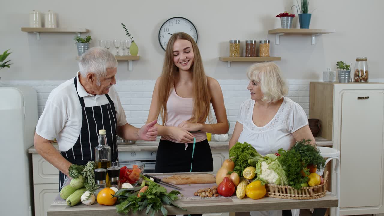 niña midiendo con cinta métrica su cintura delgada y presumiendo delante de los abuelos. dieta de alimentos crudos