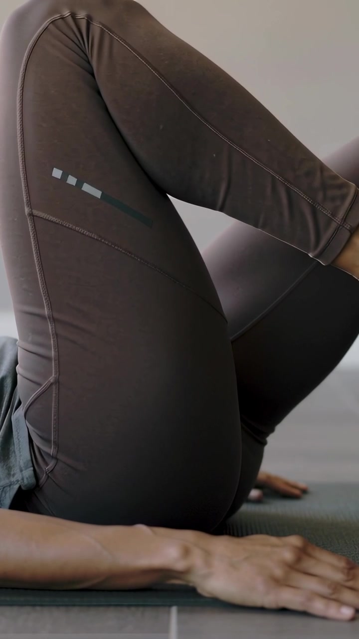 Vertical video: Lifting woman from lying on mat, for glute exercise, hands pressing, in leggings