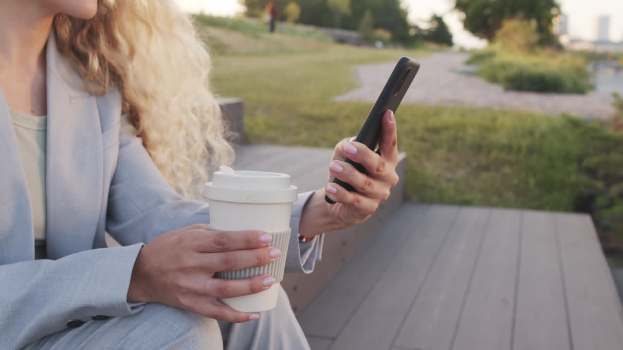 Business Woman with Coffee Cup Scrolling on Smartphone